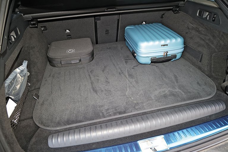 Bagagerum i en Mercedes E300 med blå kuffert og ladekabler