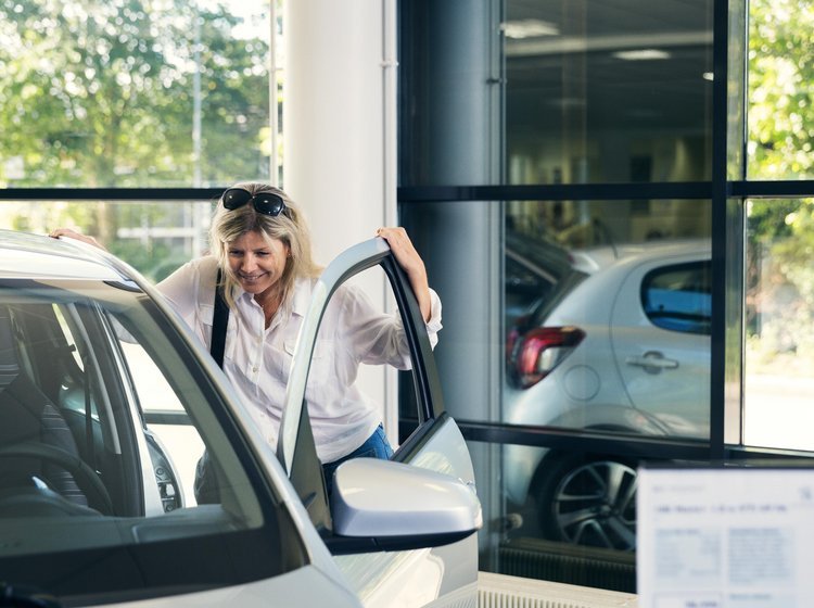 Kvinde kigger på en ny bil hos bilforhandler.