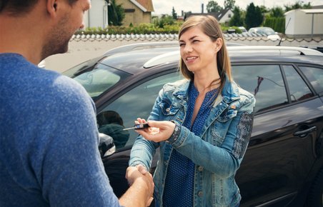Kvinde giver sin bilnøgle til en mand udenfor. 