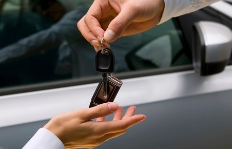 Overdragelser af bilnøgler fra en person til en anden, mens de står foran bil. 
