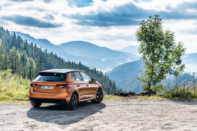 orangegylden bil holder på vej med udsigt til bjerge