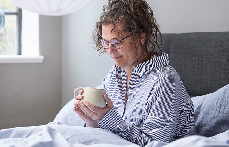 Kvinde drikker kaffe i sin seng