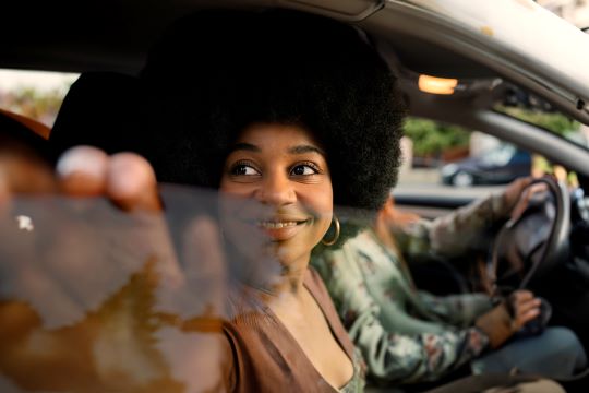 Kvinde kigger ud af bilrude og holder hånden på vindueskanten