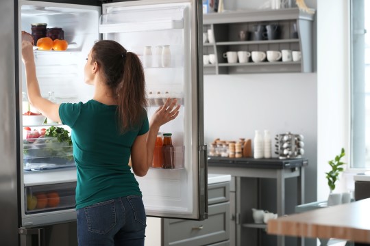 kvinde i grøn t-shirt tjekker varer i køleskabet
