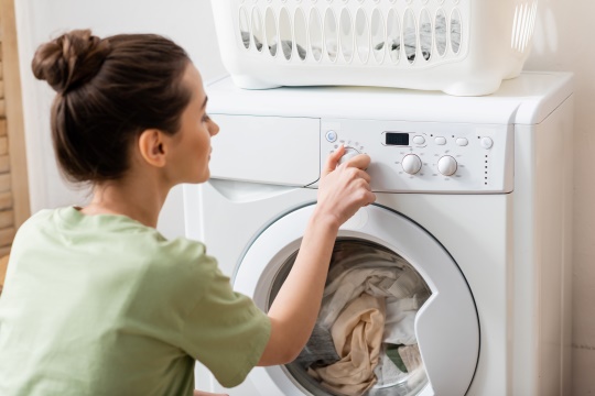 kvinder sætter vaskemaskine i gang