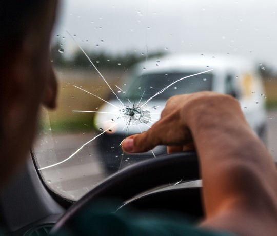 ung mand i bil med glasskade på forruden