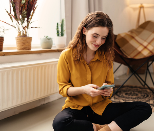 Kvinde sidder foran radiator med naturgas fra DCC Energi