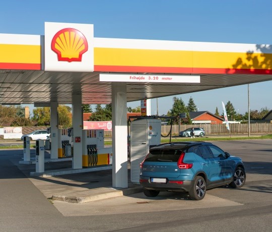 blå volvo oplader ved Shell Recharge i sommerlandskabet i Danmark 540x460