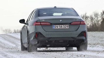 Elbilen BMW i5 set bagfra, mens den kører på en snedækket vej.