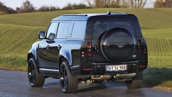 En sort Land Rover Defender set bagfra, mens den kører på en landevej.