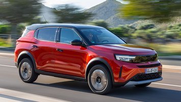 Opel Frontera set skråt forfra, mens den kører med et bjerg og træer i baggrunden
