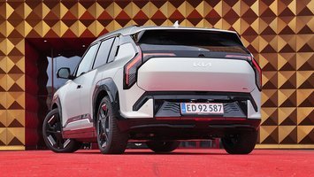 Kia EV3 elbil set bagfra, mens den holder foran guldfarvet bygning