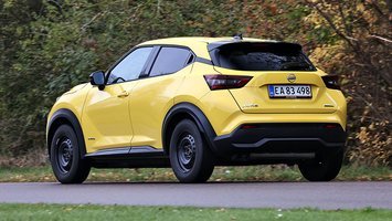 Gul Nissan Juke set bagfra, mens den kører på landevej med træer i baggrunden