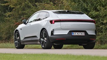 En Polestar 4 set bagfra kører på en vej med træer i baggrunden.