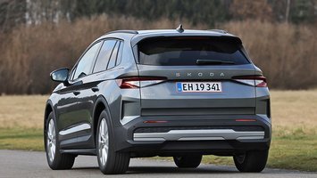Skoda Elroq 50 set bagfra, mens den kører på en landevej med træer og marker i baggrunden