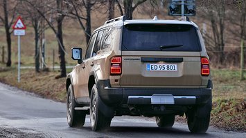 En Toyota Land Cruiser set skråt bagfra kører på landevej