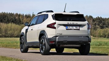 Dacia Duster set bagfra, mens den kører på landevej med træer i baggrunden