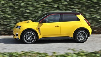 Gul Renault 5 set fra siden, mens den kører foran en hæk