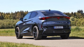 Cupra Tavascan set bagfra, mens den kører på en vej med træer i baggrunden