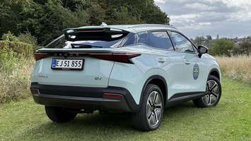 Omoda 5 EV set bagfra, mens den holder på en græsplæne