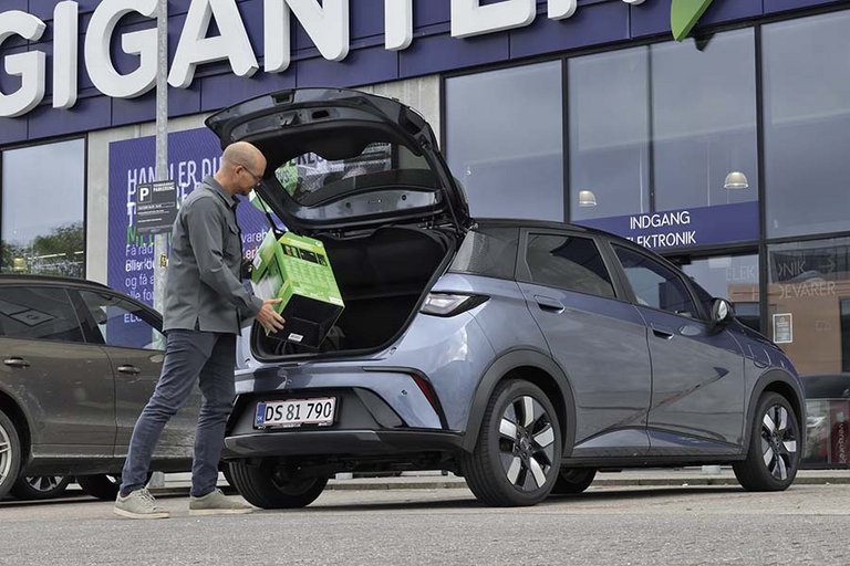 En mand pakker bagagerummet på en BYD Dolphin.