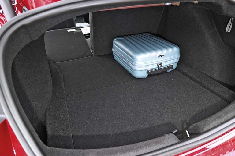 Bagagerum med blå kuffert i en Tesla Model 3