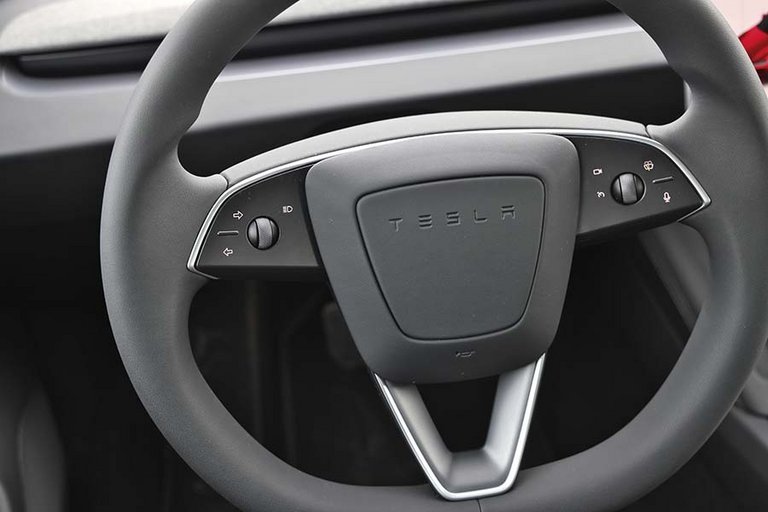 Man tænder blinklys via knapper på rattet i en Tesla Model 3