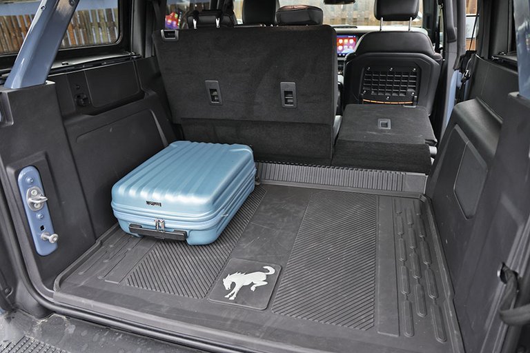Bagagerum med blå kuffert i en Ford Bronco.
