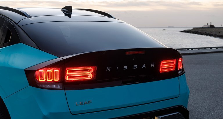 Blå Nissan Leaf bagfra med tændte baglygter.