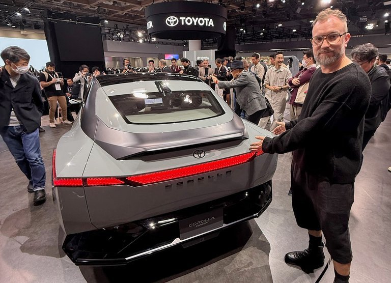 Mand ved bagende af bil på udstilling.