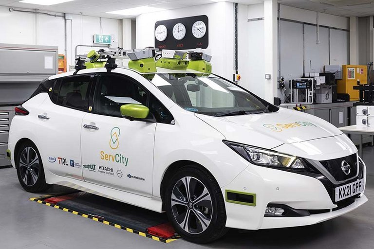 Nissan Leaf holder i laboratorium udstyret med radarer og kameraer, så bilen kan køre selv