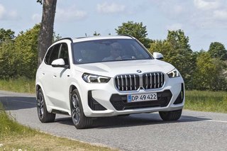 BMW X1 plugin-hybrid kører på en landevej med træer i baggrunden