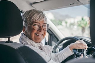 Ældre kvinde sidder på førerpladsen i en bil