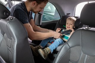 Mand spænder barn fast i autostol
