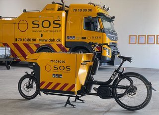 Vejhjælpscyklen er specielt bygget til SOS Dansk Autohjælp og vejer 150 kg. Trods sin høje vægt står den i kontrast til Dansk Autohjælps største bjærgningskøretøj.ntrast
