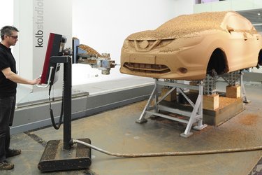 En 1:1 lermodel måles op ved hjælp af en 3D-målemaskine, der kan omsætte det håndbearbejdede design til en digital model.