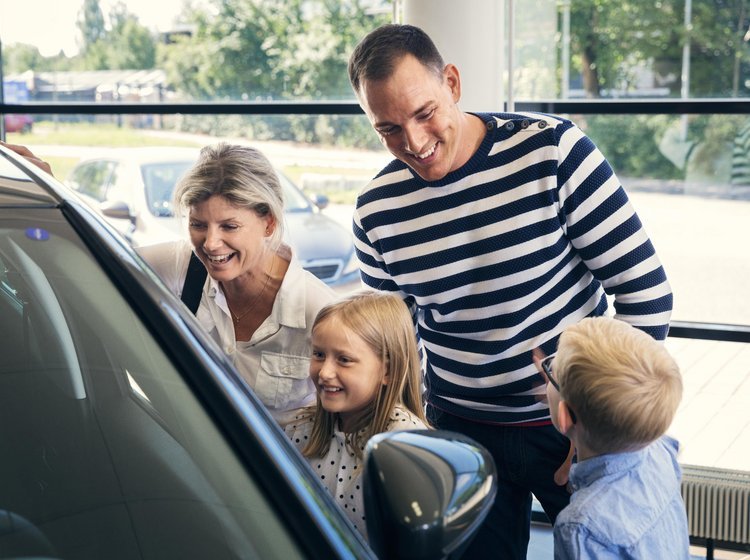 Familie kigger på bil hos bilforhandler. 