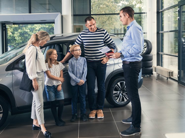 Familie taler med en bilhandler om at købe ny bil. 