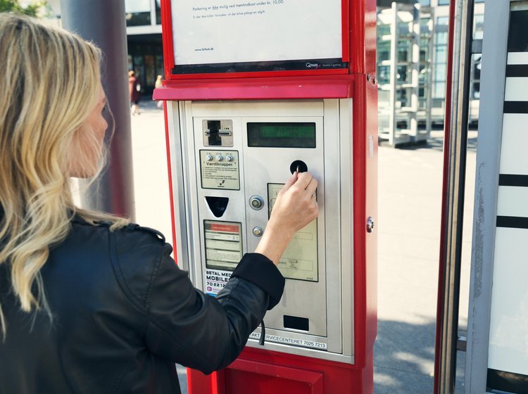 Kvinde betaler for parkering i en billetautomat.