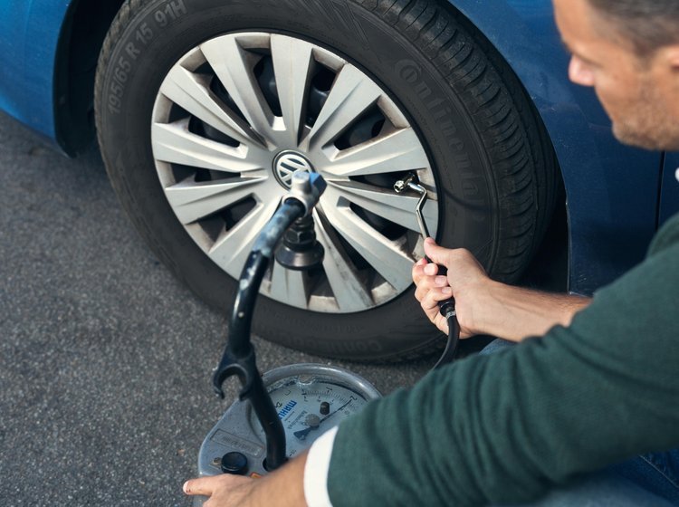 Mand justerer dæktryk på sin bil. 