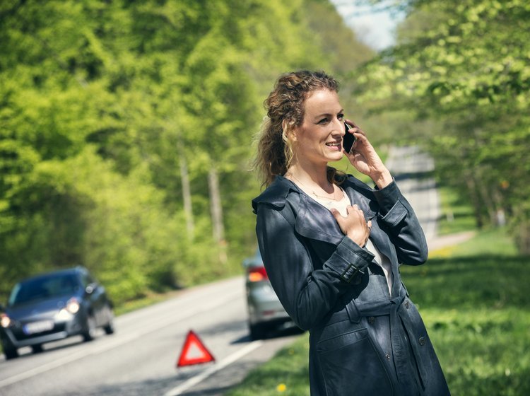Kvinder taler i telefon, efter hendes bil er stoppet i rabatten. 