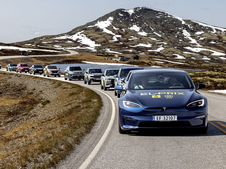 Tesla Model S kører i fjellet i Norge med en lang række elbiler bag sig. 