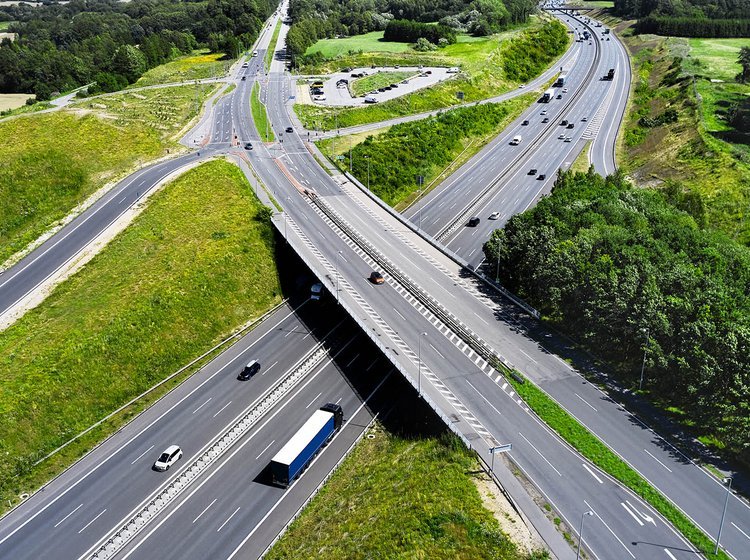 Overbliksbillede af en landevej og en motorvej der krydser hinanden. 