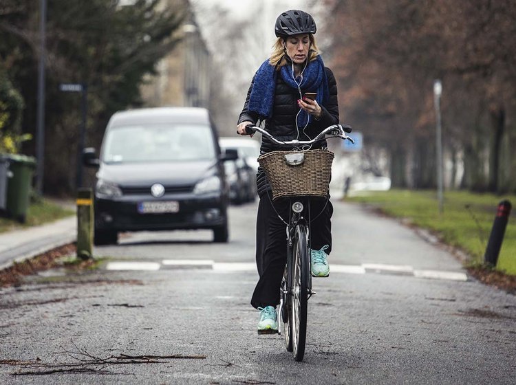 Kvinde cykler, mens hun ser på mobiltelefon