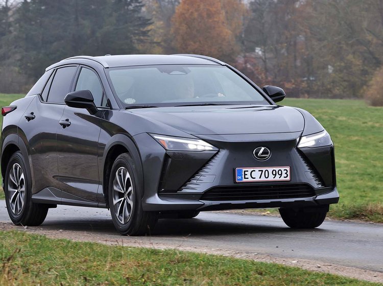 Lexus RZ set forfra, mens den kører på landevej med græs rundt om