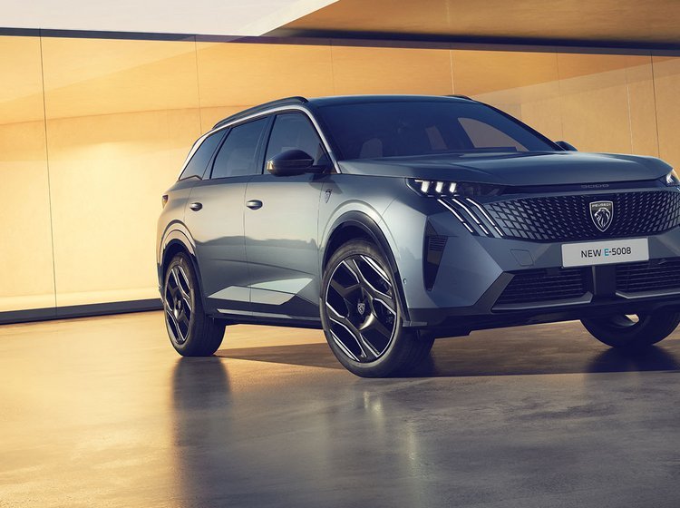 Peugeot E-5008 elbilen står med en elegant bygning i baggrunden. 