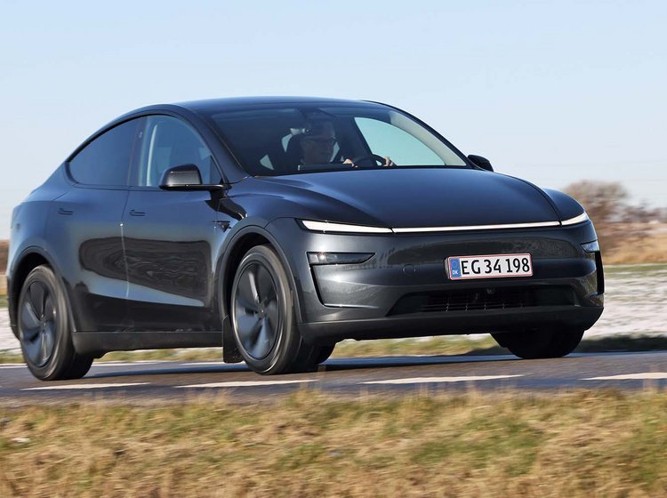 Tesla Model Y kører på landevej med sne i baggrunden
