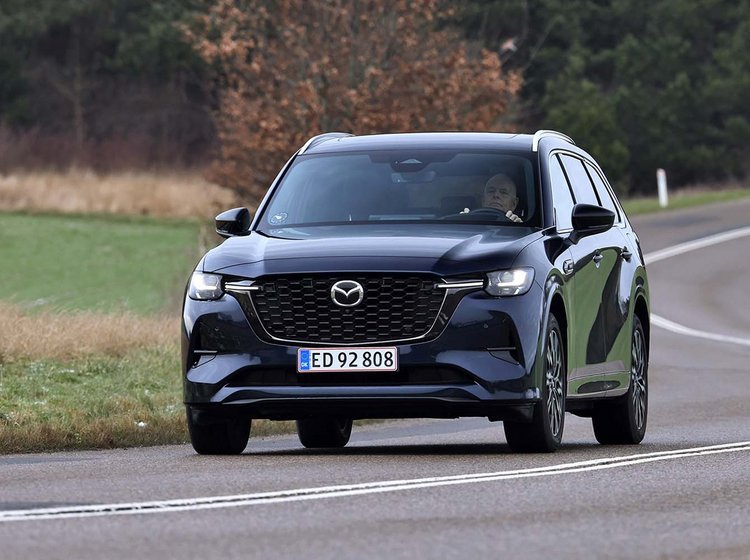 Mazda CX-80 set forfra kører i et sving på en landevej