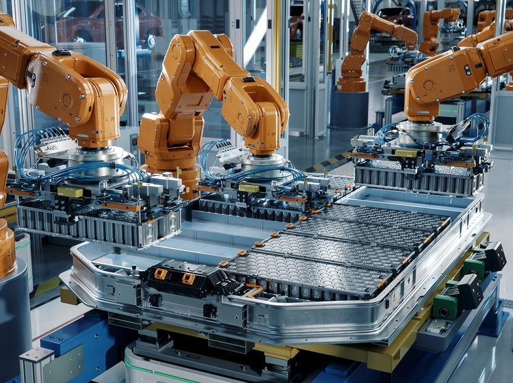 Produktion af batterier. Orange robotter samler et bilbatteri. 