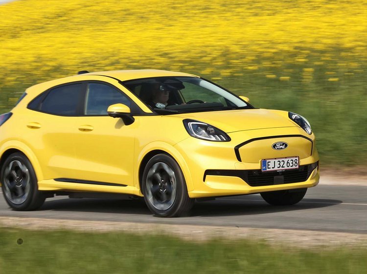 Gul Ford Puma kører på vej med rapsmarker i baggrunden